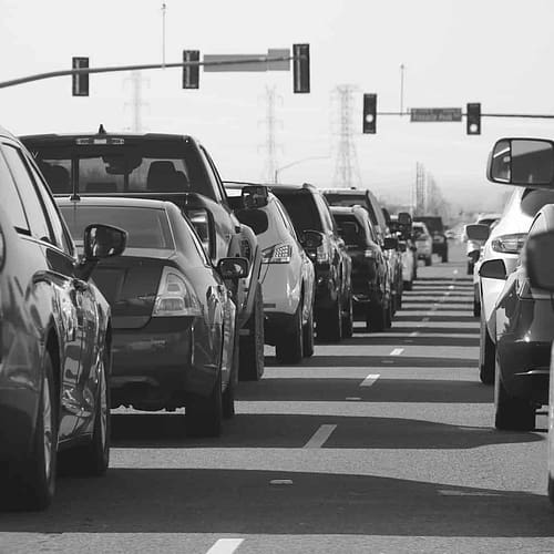 black and white image of cars lined up at a traffic light