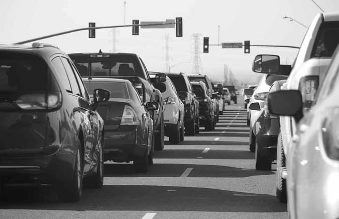 black and white image of cars lined up at a traffic light